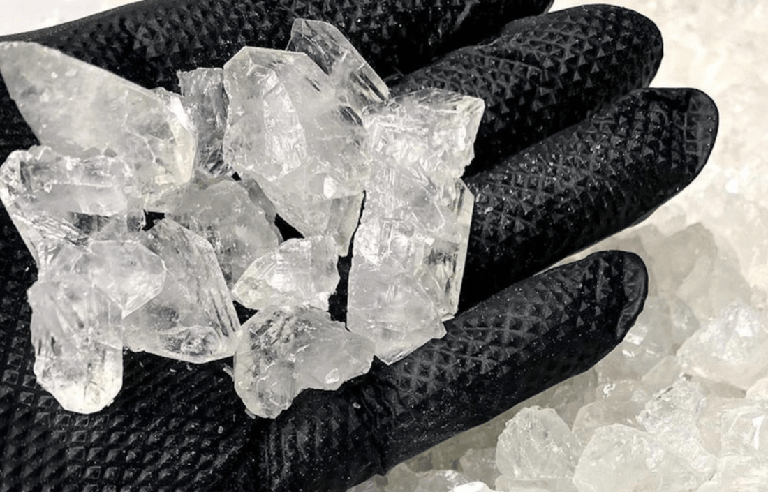 Clear crystals in a black gloved hand related to THCa Decarboxylation SOP procedure