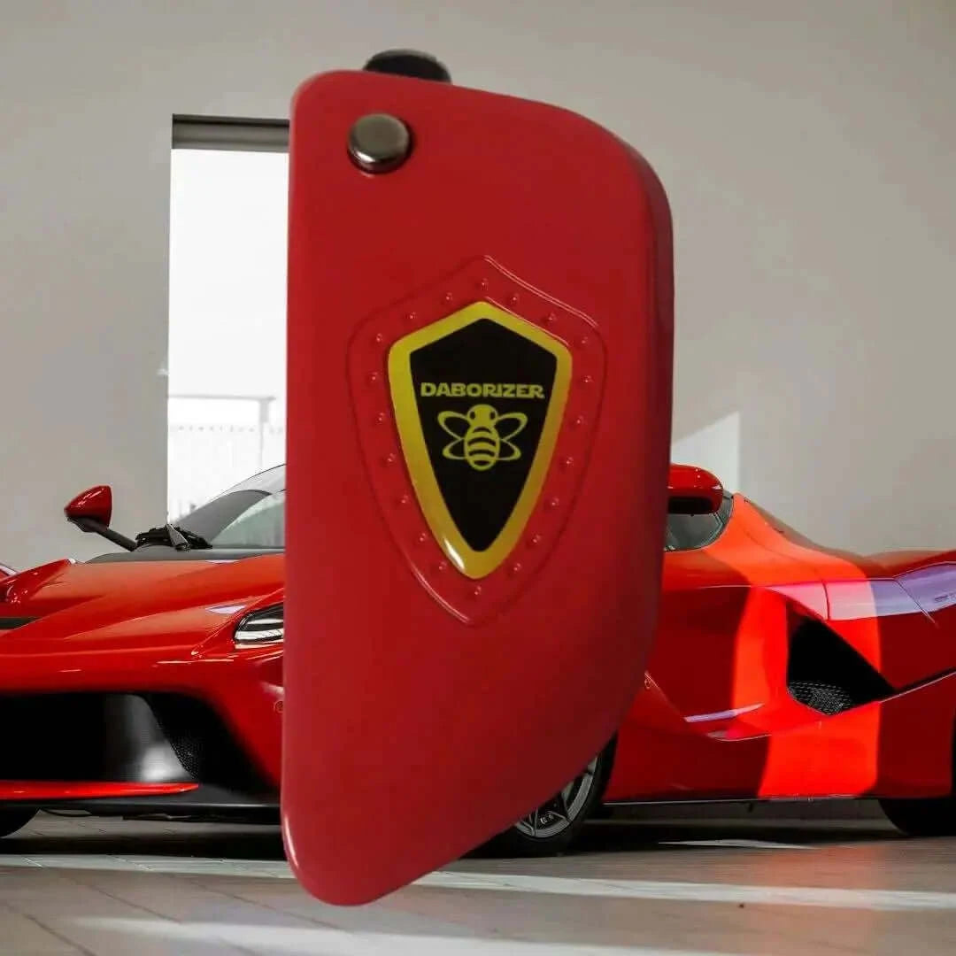 Daborizer Key FOB 510 Battery in fiery red shown with a sleek sports car in the background